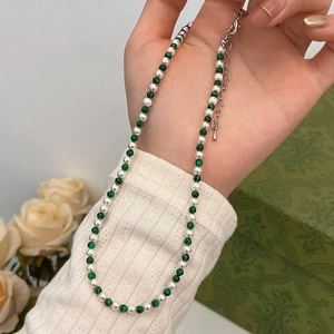 Élégant collier de perles et turquoise avec chaîne en argent présenté dans une main