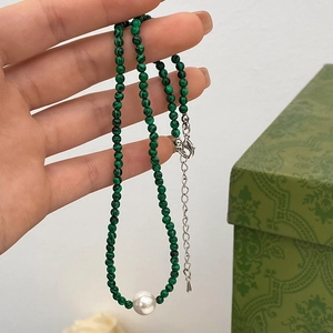 Gros plan d'un collier en perles de turquoise verte avec une perle centrale et fermoir