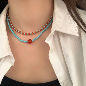 Boho layered necklace with orange agate and turquoise beads on a white shirt