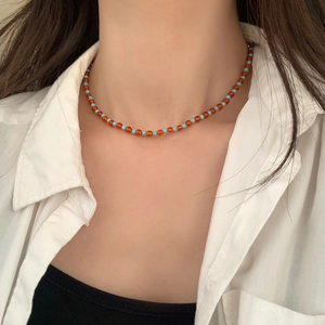 Detail view of handmade turquoise and orange beaded choker necklace on model neckline
