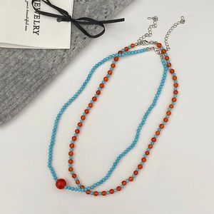 Detail of blue and orange beaded necklace set with silver clasp and red center bead