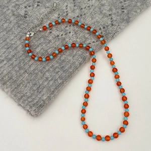 Close-up of orange and blue beaded necklace with silver lobster clasp and extension chain