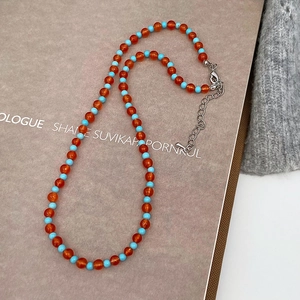 Detail of beaded necklace with orange agate-style beads and light blue turquoise accents