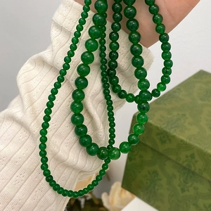 Elegant green chalcedony beaded necklace layers displayed on a textured sleeve and box