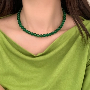 Close-up of a green chalcedony beaded necklace worn on a matching green silk blouse