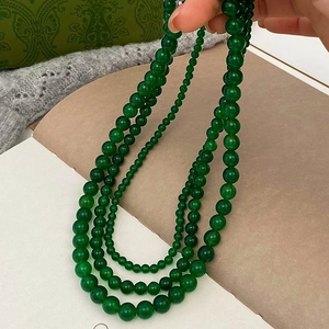 Close-up of three sizes of green chalcedony beaded necklaces with glossy texture