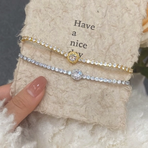 Detail of silver and gold tennis bracelets with halo round center stone and zircon inlays
