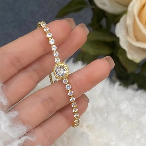 Close-up of a gold micro-set zircon tennis bracelet with a brilliant halo centerpiece