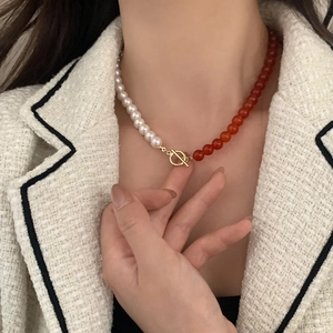 Close-up of red agate and white pearl beaded necklace with gold toggle OT clasp detail