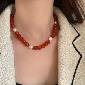 Elegant red agate necklace with baroque pearls and gold beads on a model's collarbone