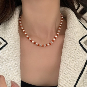 Elegant beaded necklace with red agate and white pearls on a tweed jacket background