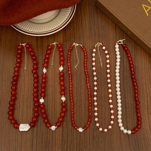 Detail of red agate and pearl beaded necklaces with gold accents on vintage background