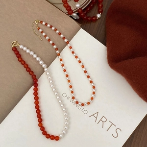 Close-up of pearl and red agate beaded necklace set with golden OT toggle clasp