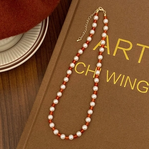 Detailed shot of red agate and white pearl beaded necklace with golden lobster clasp
