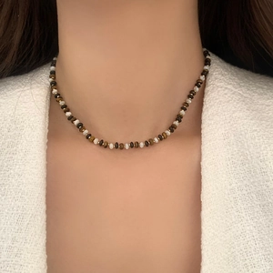 Gros plan du collier vintage en perles d'œil de tigre porté par une femme