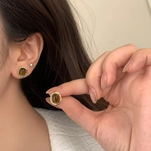 Gros plan de boucles d'oreilles vintage en or avec pierres oeil de tigre sur modèle