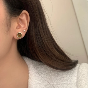 Détail de la boucle d'oreille ronde vintage avec pierre œil-de-tigre et bord doré
