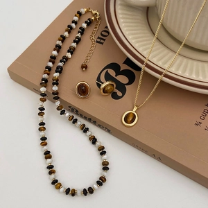 Gros plan sur un ensemble de bijoux vintage en oeil de tigre avec collier perlé doré