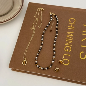 Détail d'un ensemble de colliers en œil de tigre et boucles d'oreilles dorées sur livre