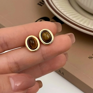 Gros plan sur des boucles d'oreilles ovales vintage en œil de tigre avec monture dorée