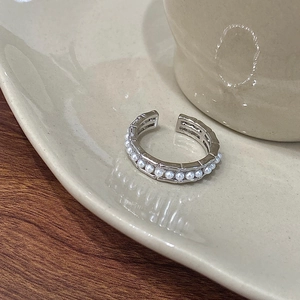 Detailed macro view of adjustable silver ring featuring a row of white pearls on ceramic