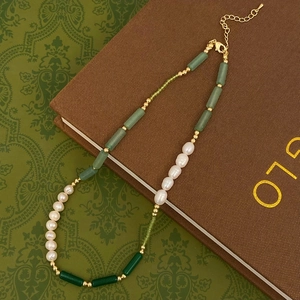 Detail of freshwater pearl and green gemstone necklace with gold clasp on vintage book