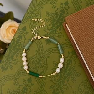 Detailed shot of freshwater pearl and green stone bracelet with golden lobster clasp