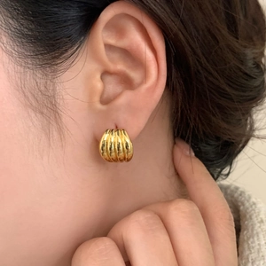Elegant gold croissant dome earrings with ribbed texture shown on a female model