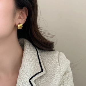 Detail of elegant gold croissant dome earrings showing layered wave texture on ear
