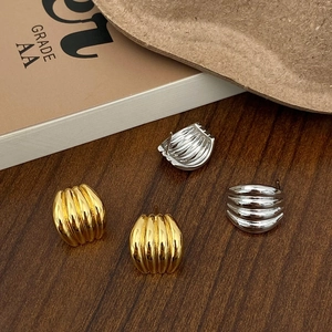 Macro detail of textured gold and silver croissant dome stud earrings on wood