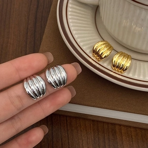 Close-up of gold and silver croissant earrings with textured metal finish on a tray