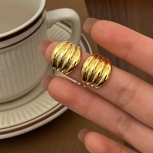 Detailed close-up of chunky gold hoop earrings with a polished twisted croissant design