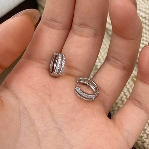 Close-up of minimalist silver hoop earrings with micro-set zircons held in hand