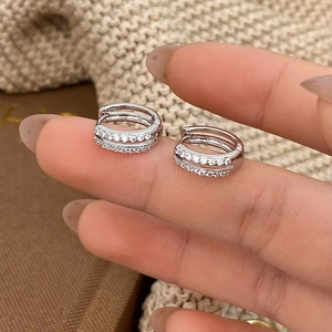 Detail of silver double hoop earrings with micro-pave cubic zirconia held by hand