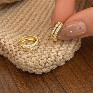 Macro shot of gold hoop earrings with double row cubic zirconia on knit fabric