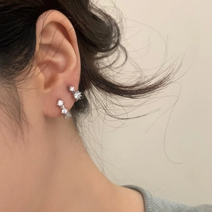 Close-up of sparkling silver cubic zirconia hoop earrings worn by a model in a layered style