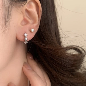 Minimalist silver zirconia drop earrings and gold solitaire stud on model ear