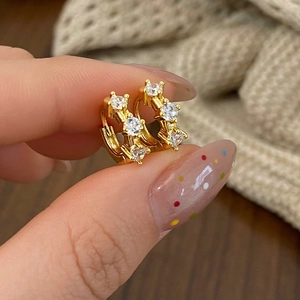 Detailed view of gold hoop earrings with sparkling round cubic zirconia stones held by hand