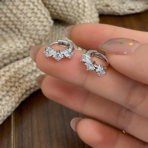 Close-up of minimalist silver hoop earrings with three sparkling round zircons