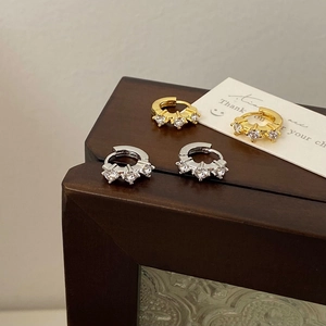 Minimalist gold and silver cubic zirconia hoop earrings displayed on a dark wood box
