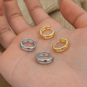 Minimalist double-layered gold and silver hoop earrings shown held in hand