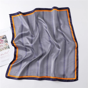 Detail of silk square scarf featuring black and white houndstooth pattern and orange borders