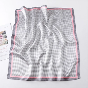 Detailed view of grey houndstooth square silk scarf with pink border on magazine