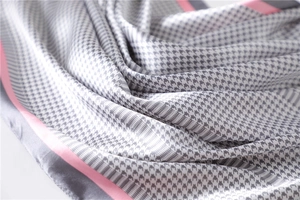 Detailed view of houndstooth silk scarf texture with pink borders and satin luster
