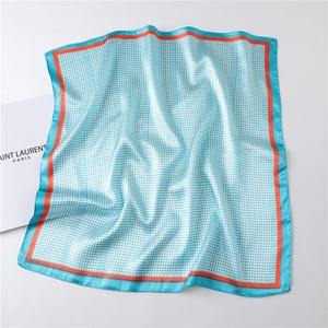 Detail of blue houndstooth silk scarf with bright orange borders and satin finish