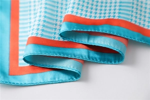 Macro detail of houndstooth silk scarf with elegant orange border and smooth texture