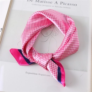 Detail of pink and white houndstooth silk scarf with elegant knotted design and blue border