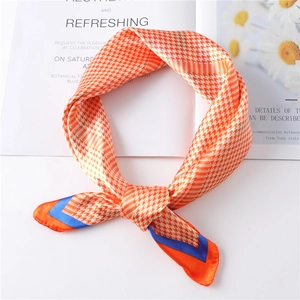 Detail of orange houndstooth silk scarf with royal blue edges on a floral magazine background