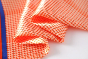 Macro detail of houndstooth silk scarf showing smooth texture and contrast blue edges