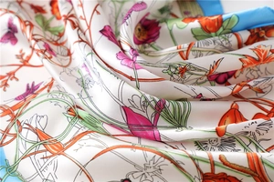 Detailed close-up of floral print silk scarf with vibrant butterfly and insect patterns